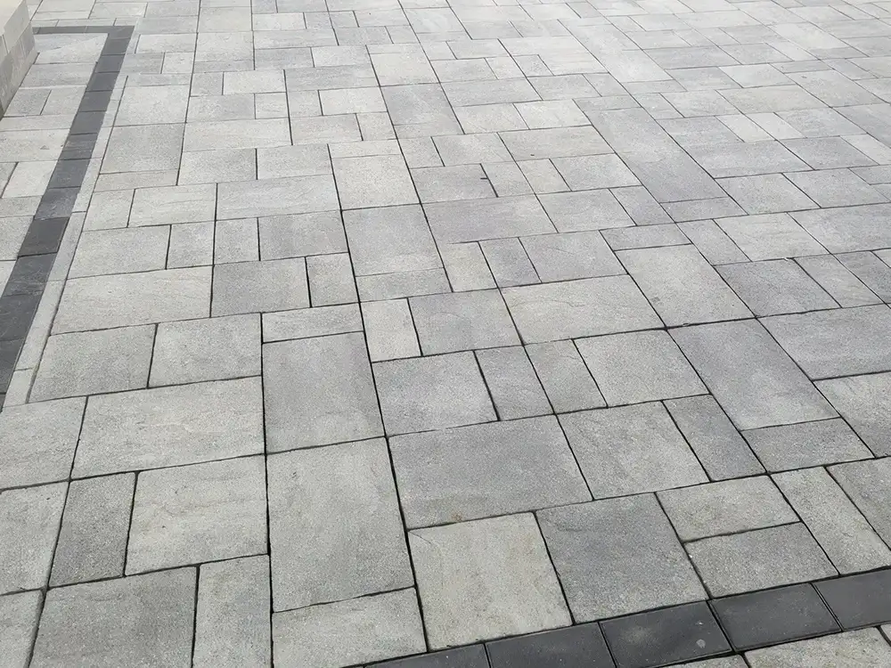 beautiful grey and charcoal flat stone patio of varying sizes with in an irregular shape.